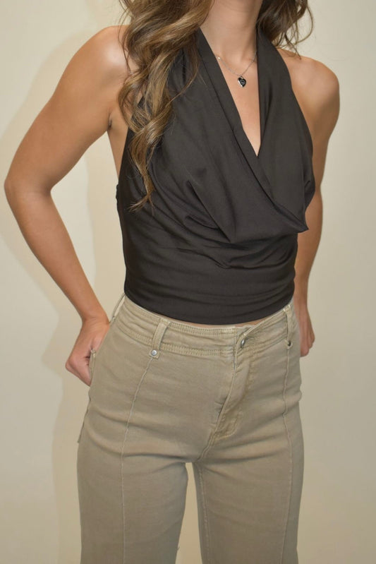 Woman wearing a brown halter top and beige pants against a plain background