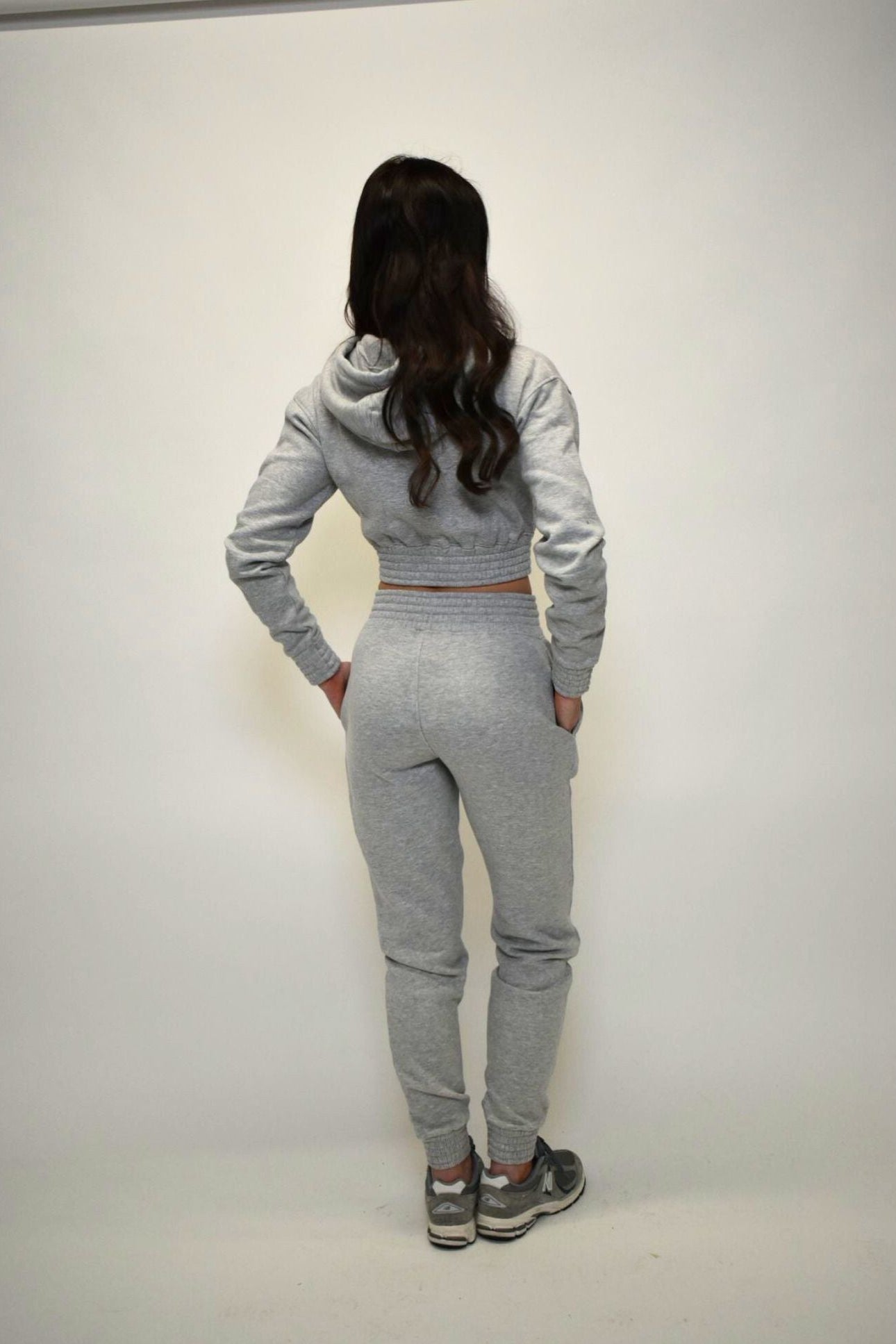 Person wearing a gray tracksuit against a white background